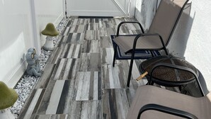 Eine Terrasse mit weißem Zaun, zwei Liegestühlen und dekorativen Froschfiguren.