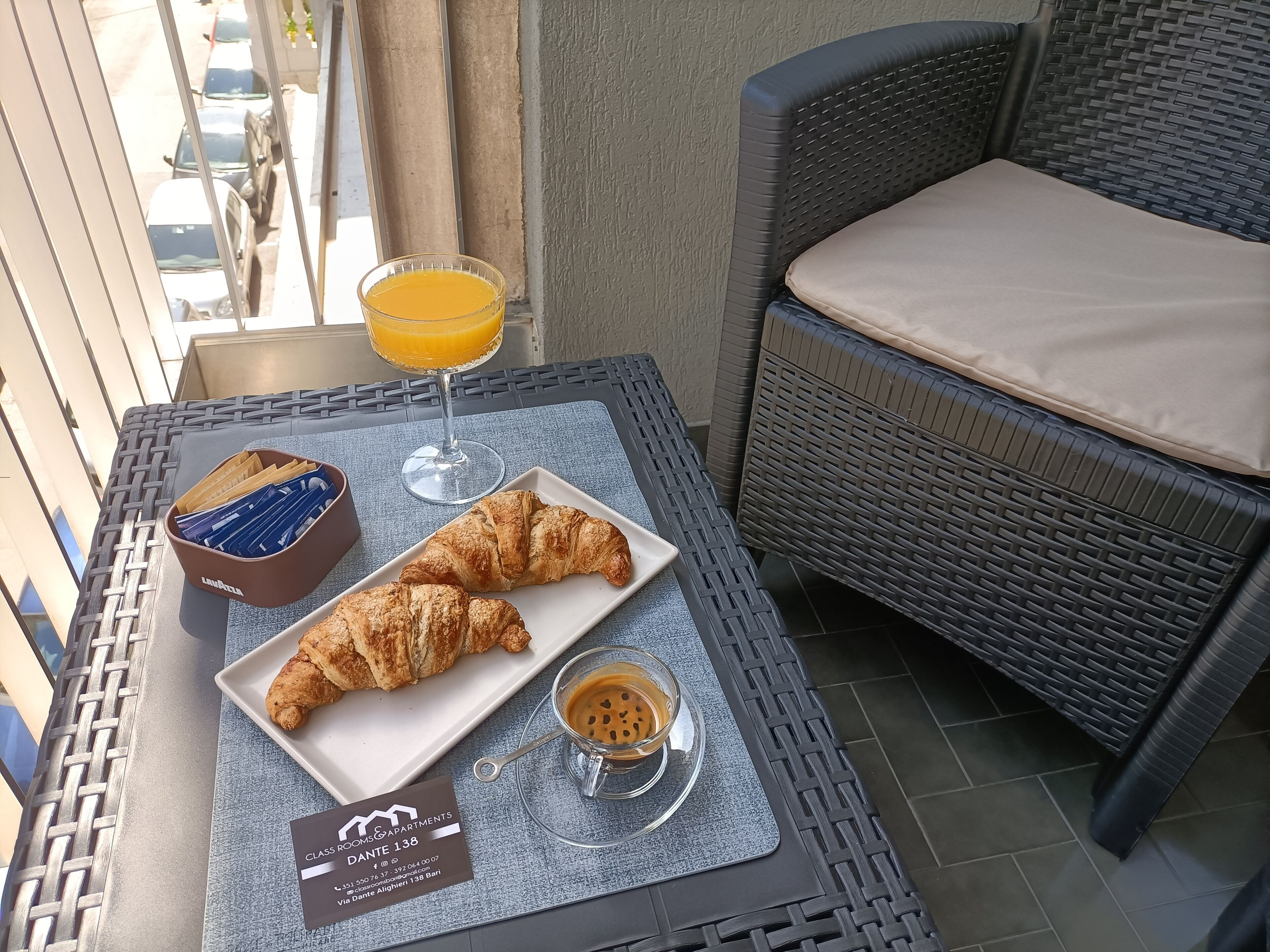 A breakfast tray with croissants, orange juice, and coffee on a balcony table.