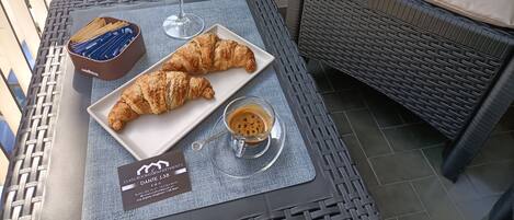 A breakfast tray with croissants, orange juice, and coffee on a balcony table.