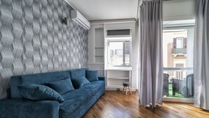 Un salon moderne avec un canapé bleu, un plancher en bois et un mur orné de motifs.