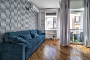 Ein modernes Wohnzimmer mit einem blauen Sofa, Holzboden und einer Wand mit Muster.