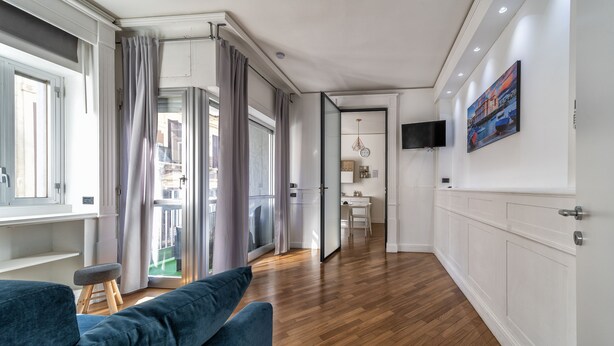 Un salon moderne avec un canapé bleu, un parquet en bois et une vue sur l’extérieur.