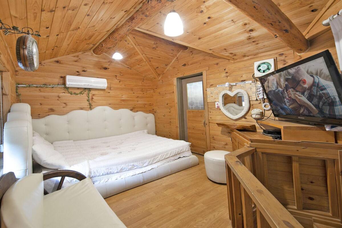 A wooden cabin room with a bed, a television, and a small table.