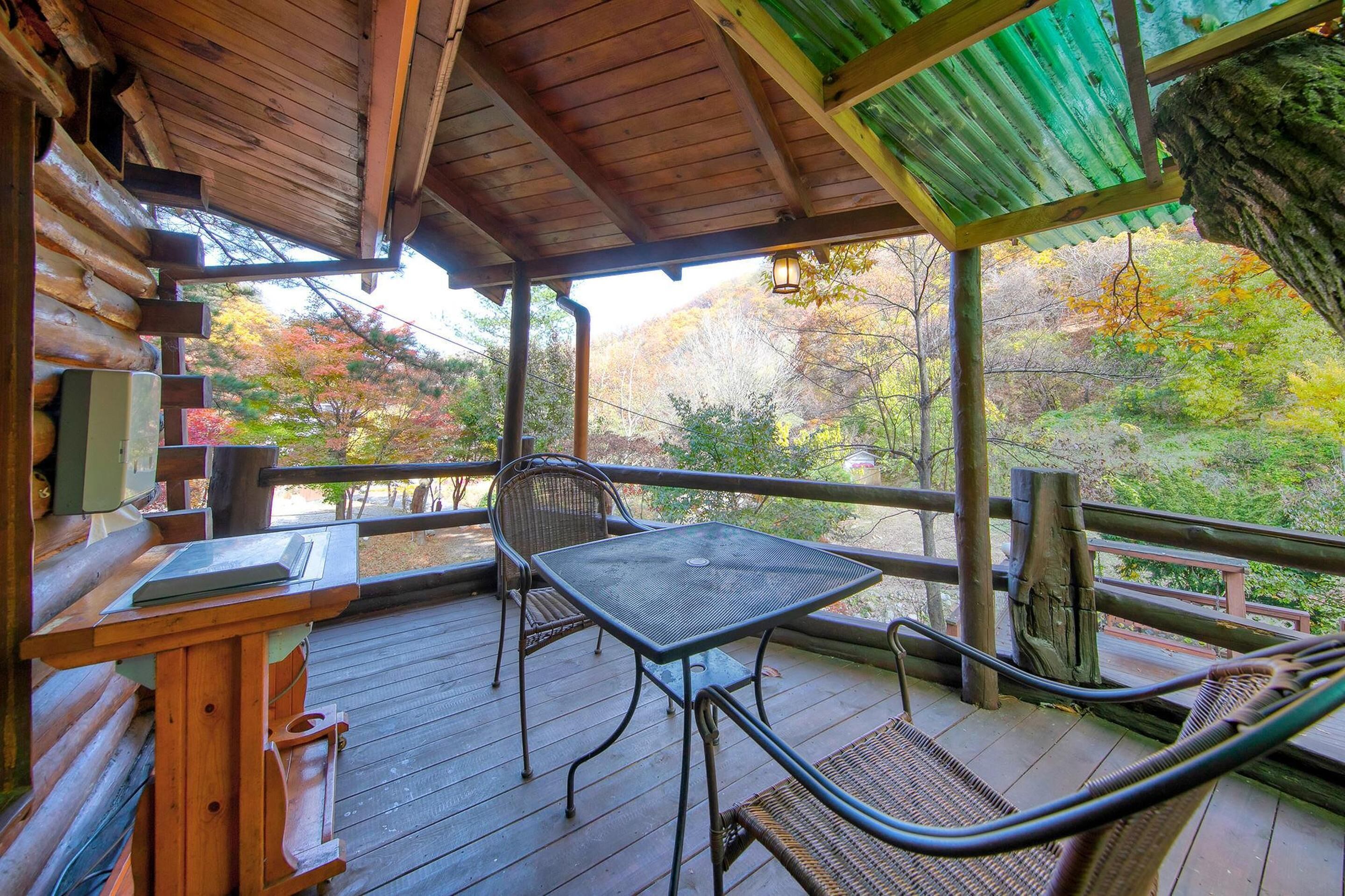 A wooden deck with a table and chairs, overlooking a forested area.