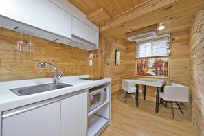 A modern kitchen with a sink, microwave, and white cabinets. There is a dining area with a table and chairs, and a painting on the wall. - Gapyeong Belita Pension (Gapyeong)