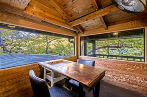 A wooden interior with a table and chairs, large windows with a view of trees, and a ceiling fan. - Gapyeong Belita Pension (Gapyeong)