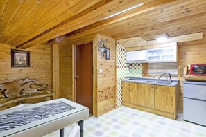 A wooden cabin interior with a kitchen area, a dining table, and a framed picture on the wall. - Gapyeong Belita Pension (Gapyeong)