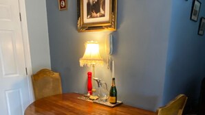 A dining table with chairs, a lamp, a bottle, and a candle on a wooden floor. - Beautiful Town Centre Apartment With River Terrace (Macclesfield)