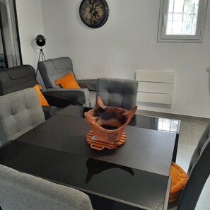 Ein modernes Wohnzimmer mit einem Glastisch, grauen Sofas und einer dekorativen Keramikschale.
