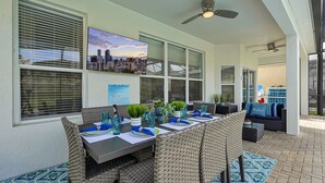 A dining area with a view of the city skyline, outdoor seating, and a ceiling fan. - Luxurious home 2 miles from  Disney - Windsor Hills Resort (Kissimmee)