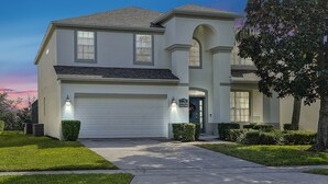 A two-story house with a white exterior, a garage, and a well-maintained lawn. - Luxurious home 2 miles from Disney - Windsor Hills Resort (Kissimmee)