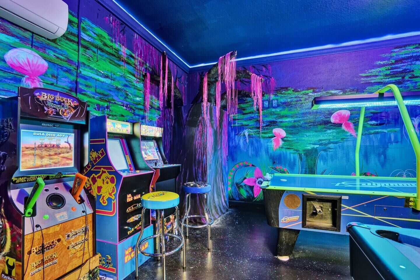 A room with arcade machines, a pool table, and a mural of an underwater scene.