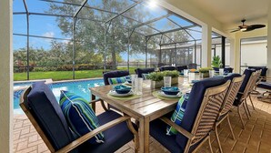 A covered patio with a pool, dining table, chairs, and a ceiling fan. - Luxurious home 2 miles from Disney - Windsor Hills Resort (Kissimmee)