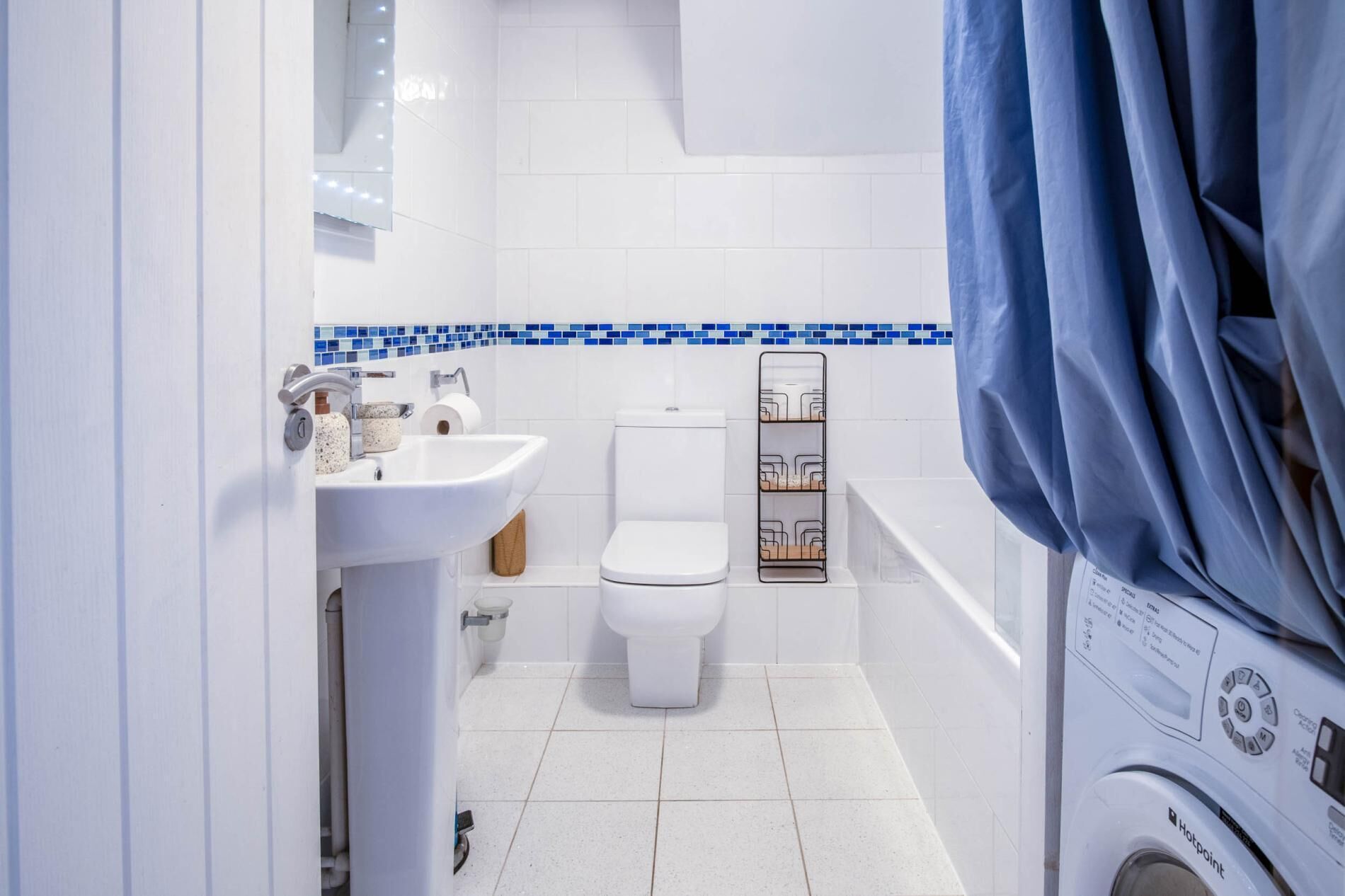 A compact bathroom with a sink, toilet, and a washing machine.