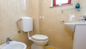 Een badkamer met toilet, hygiëneschuimer en wastafel.