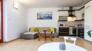Een moderne woonkamer met een bank, een ronde tafel en een keuken met kasten en apparatuur.