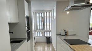 A modern kitchen with white cabinetry, a wooden countertop, and a view through a window. - 2 BED DUPLEX APARTMENT IN THE HEART OF LAS AMERICAS (Playa Delas Americas)