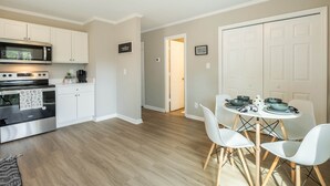 Une cuisine moderne avec des meubles blancs, un four à micro-ondes, une cuisinière et un coin repas comprenant une table et des chaises.
