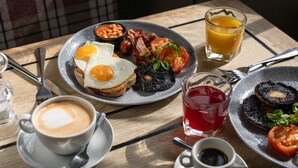 A breakfast table with eggs, beans, bacon, tomatoes, mushrooms, and a glass of orange juice. - The White Hart (Chippenham)