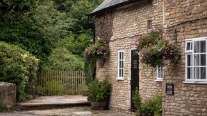 A stone building with a wooden door and flower boxes. - The White Hart (Chippenham)
