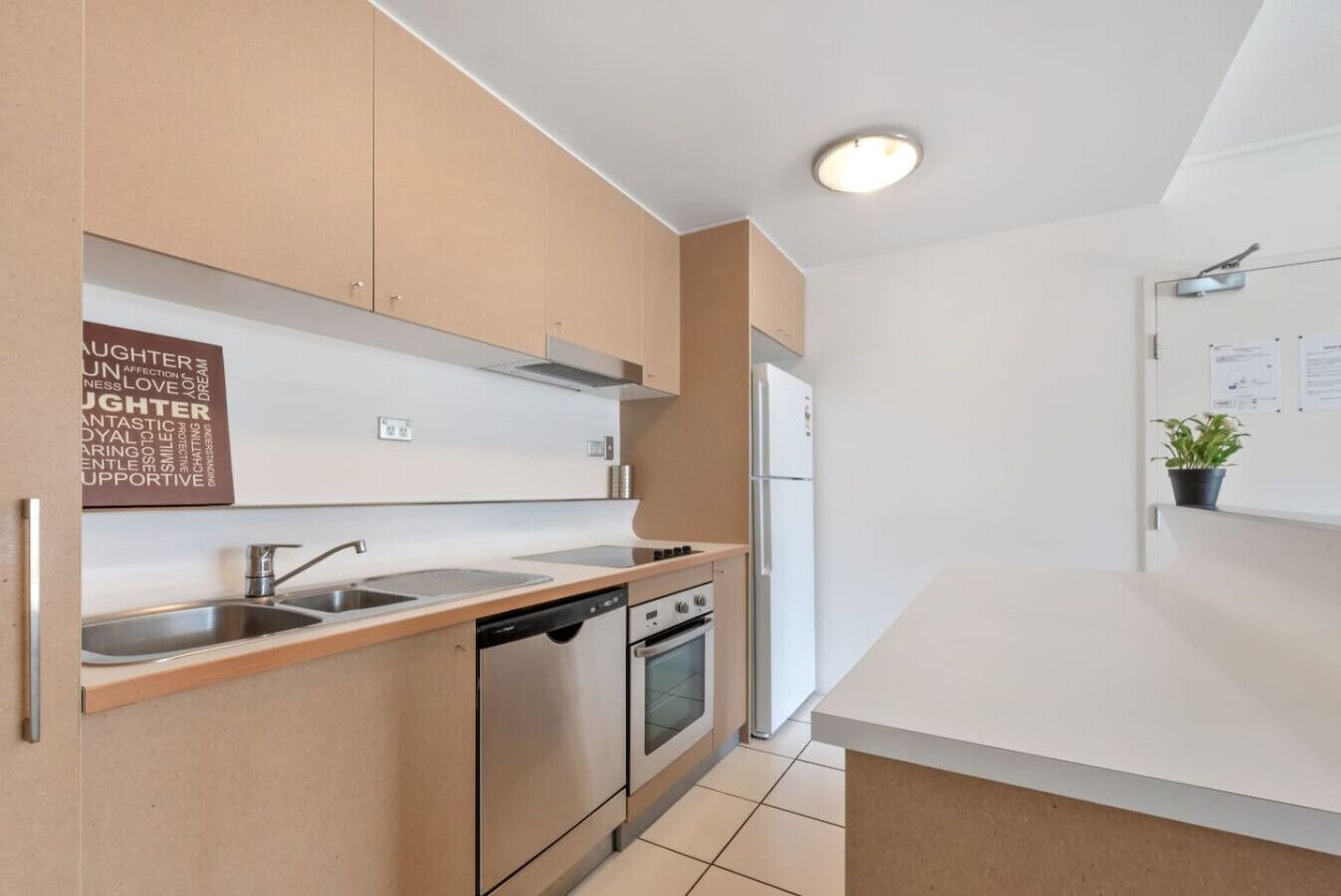 A modern kitchen with stainless steel appliances, a built-in dishwasher, and a white countertop.
