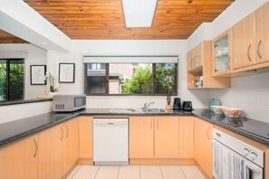 A modern kitchen with wooden cabinets, a dishwasher, a microwave, and a coffee maker.