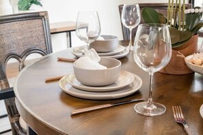 Una mesa redonda para comer con un tazón de arroz, dos copas de vino, palillos y un tenedor.