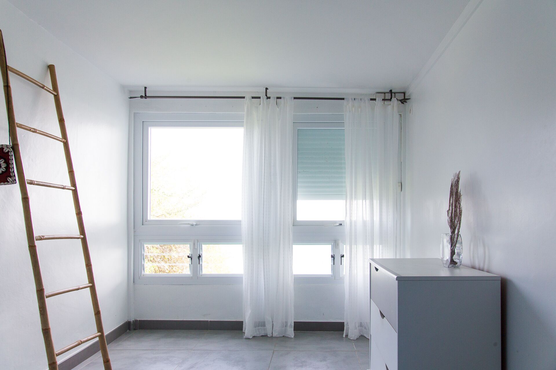Una habitación con ventana, escalera y armario.