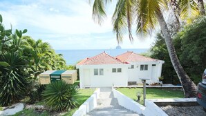 A white building with a red roof, surrounded by tropical vegetation and a view of the ocean. - Alexandra TURQUOISE (Le Diamant)