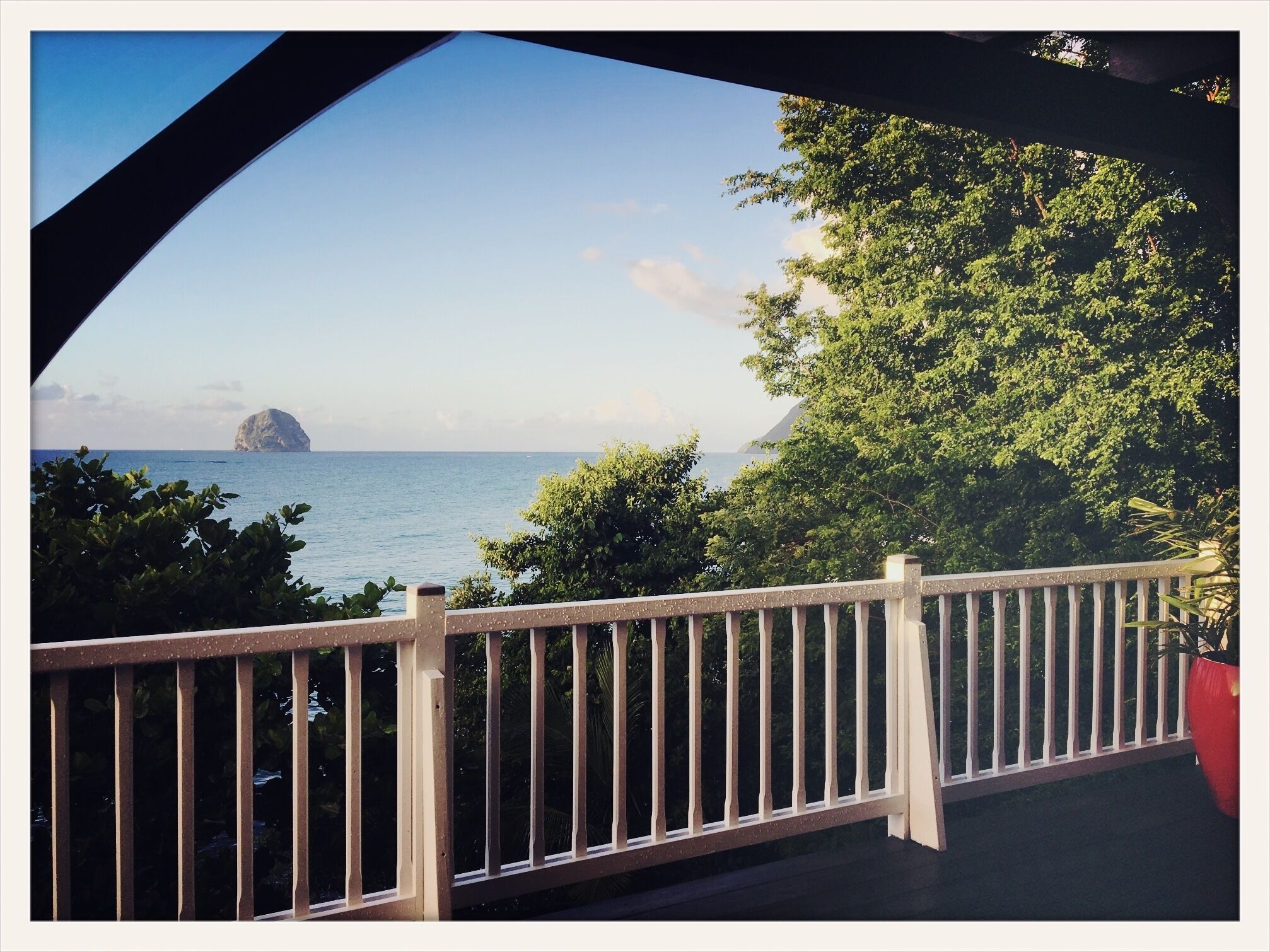 A balcony with a view of the sea and a distant island.