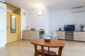 Eine moderne Küche mit Esstisch, Schränken, einem Fernseher und einer Uhr an der Wand.