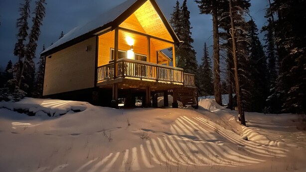 A wooden cabin with a balcony, surrounded by snow and trees. - Luxury Stargazer Cottage - Joby Chungo  (Nordegg)