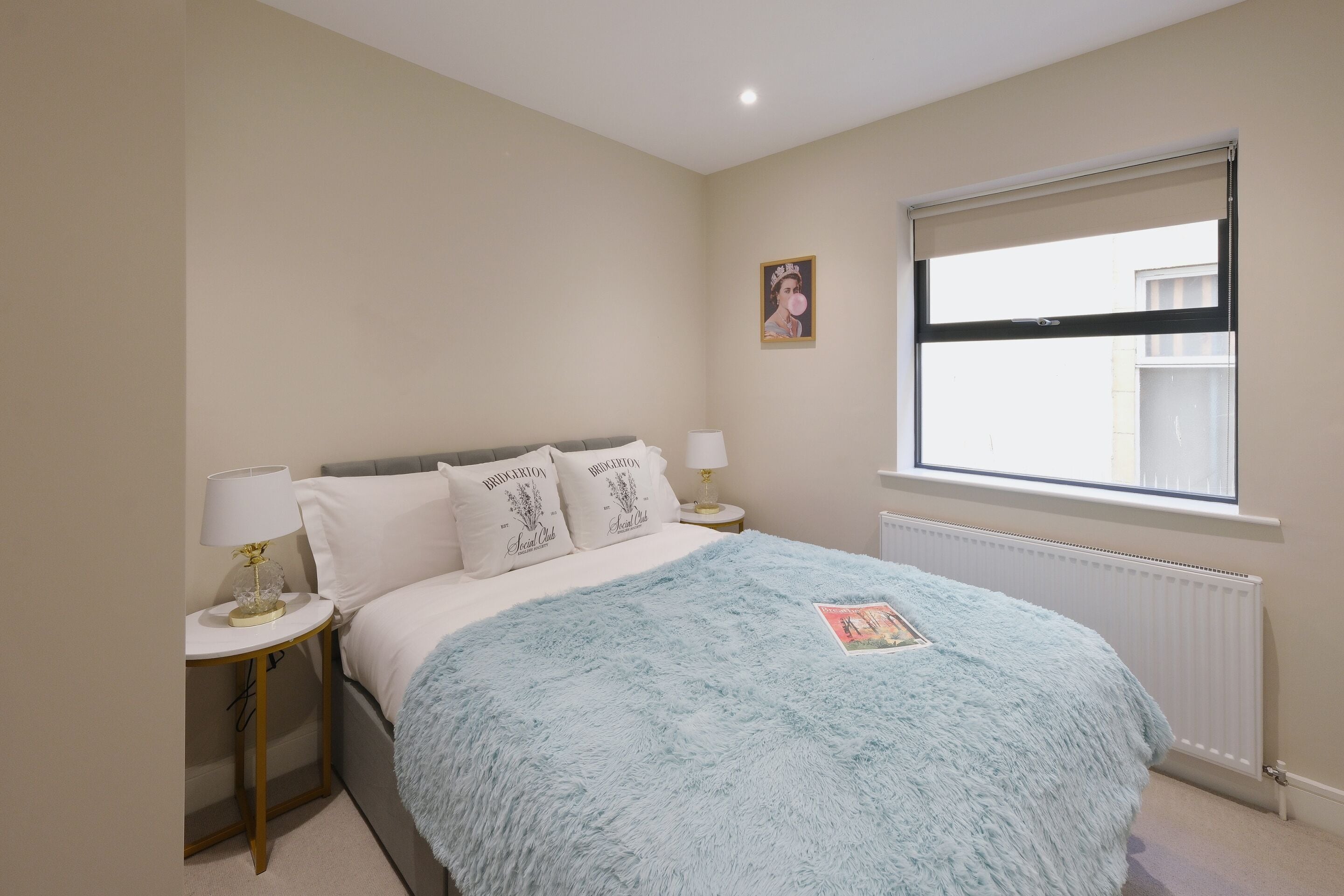 Une chambre à coucher avec un lit, une table de chevet, une fenêtre et un radiateur.