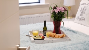 Ein Frühstücksbrett mit Croissants, Obst und Saft auf einem flauschigen, blauen Teppich.