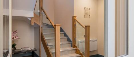 A staircase with wooden railings and carpeted steps, leading to an apartment.