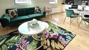 Ein Wohnzimmer mit einem grünen Sofa, einem runden Couchtisch und einem Teppich mit floralem Muster.