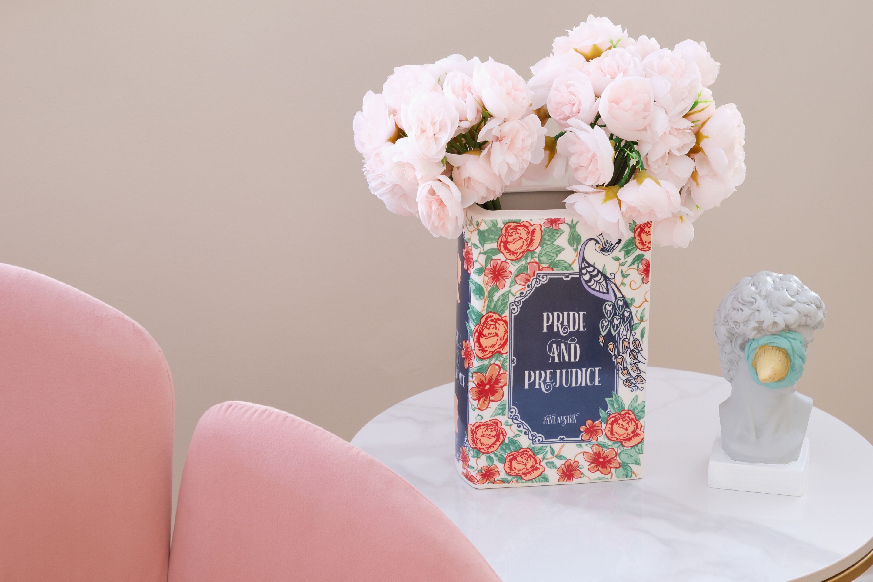 A vase with pink flowers on a white table.