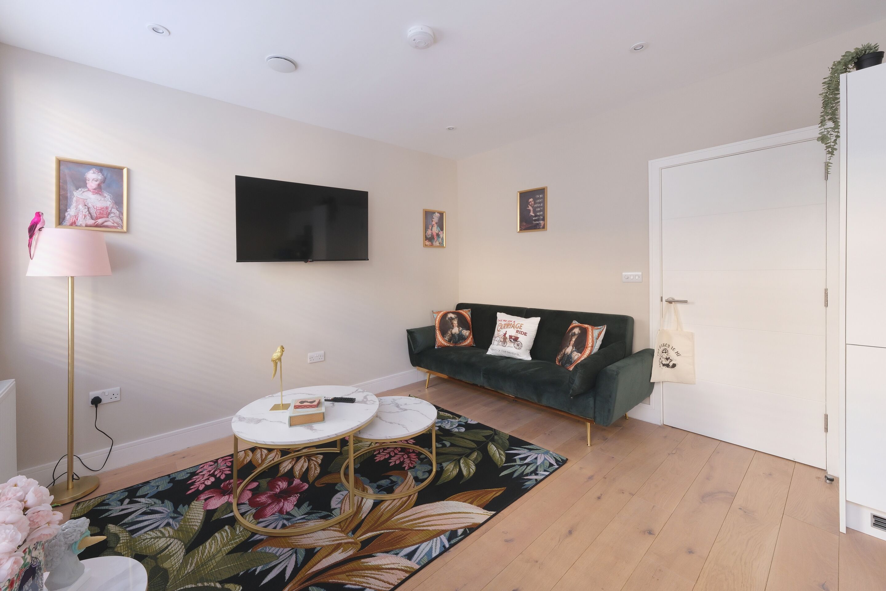 A modern living room with a sofa, a flat-screen TV, and a floral rug.