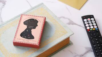 A tarot deck box on a book with a remote control beside it.