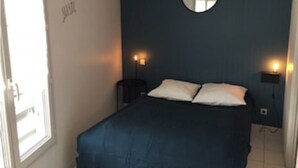 A bedroom with a bed, two bedside lamps, a round mirror on the wall, and a window. - LE COURLIS, Residences RE LOCATIONS VANCES VILLA Re (Saint-Clément-des-Baleines)