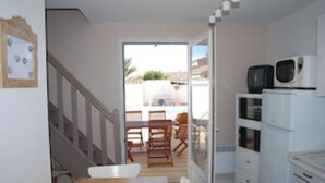 A compact kitchen with a dining area, a staircase, and a view of the outside. - LE COURLIS, Residences RE LOCATIONS VANCES VILLA Re (Saint-Clément-des-Baleines)