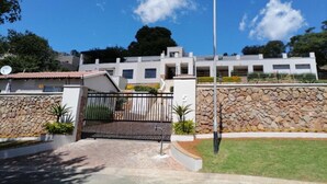 A modern building with a stone wall and a metal gate. - SkyView, a spacious modern cottage. (Johannesburg)