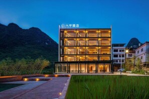 A multi-story hotel with a modern design, featuring a glass facade and multiple balconies.