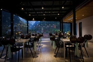 A restaurant with tables set for dining, a view of the outdoors, and a modern interior design.