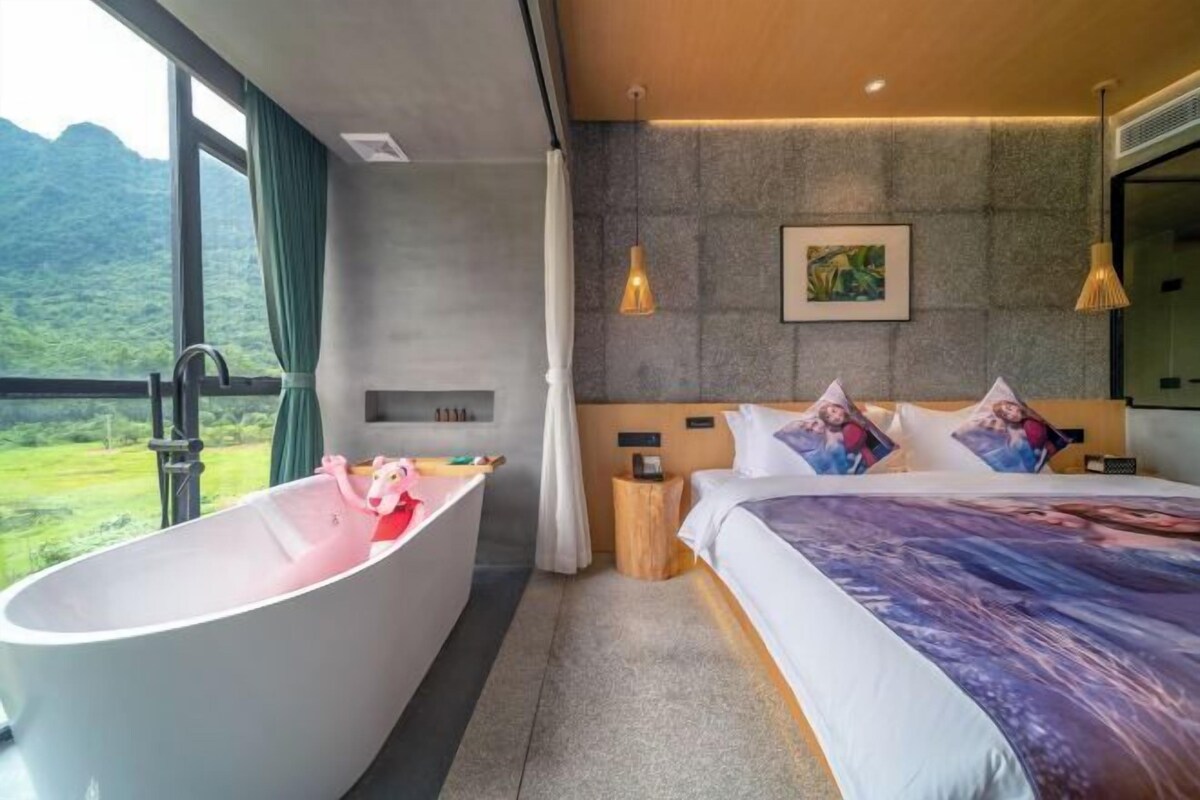 Ein modernes Hotelzimmer mit einem großen Bett, einer Badewanne und Blick auf eine Berglandschaft.