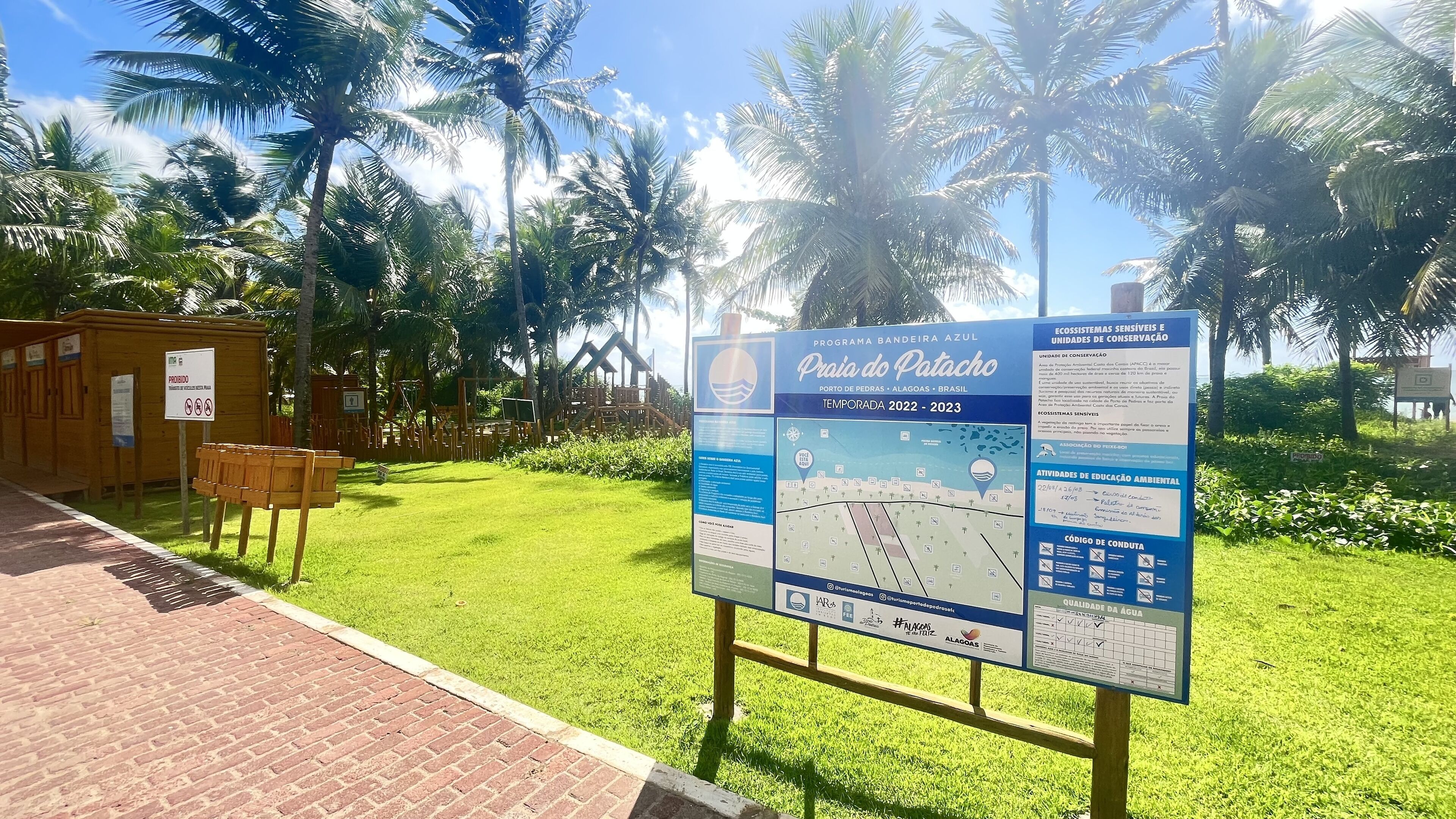 Uma placa de informação sobre a Praia do Patacho, incluindo um mapa e detalhes sobre atividades de educação ambiental.