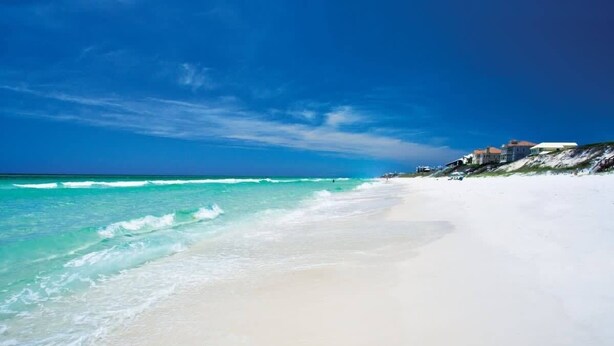 A beach with clear turquoise water and white sand, with houses visible in the background. - New Golf Cart | Resort Style Pool | 3 Bikes | 30A (Panama City Beach)