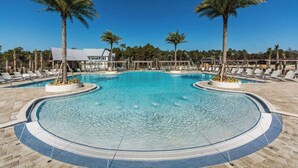 A large, clear swimming pool with lounge chairs and palm trees, surrounded by a tiled deck. - New Golf Cart | Resort Style Pool | 3 Bikes | 30A (Panama City Beach)