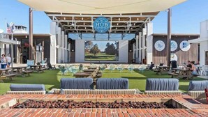 An outdoor seating area with a covered stage, picnic tables, and a brick fire pit. - New Golf Cart | Resort Style Pool | 3 Bikes | 30A (Panama City Beach)