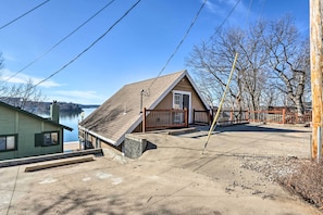 Ein Haus mit schrägem Dach, einer Holzterrasse und Blick auf einen See.